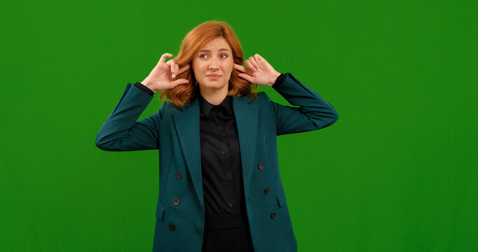 A woman in a teal suit stands in a studio with a green background showing various gestures. She appears playful and animated while engaging with the camera. - Powered by Adobe