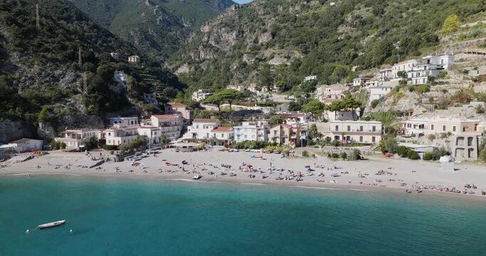 Aerial view of Erchie beach, where azure waters meet the shore, nestled beneath lush green mountains and charming architecture, Erchie, Amalfi Coast, Italy.