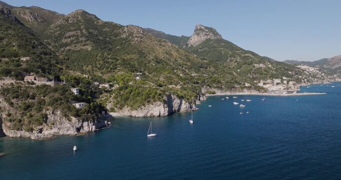 Aerial view of the Erchie coastline dotted with boats, contrasting the deep blue sea with the lush green mountains, Erchie, Amalfi Coast, Italy.