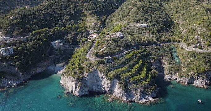 Aerial view of winding road hugging the Amalfi coast, contrasting with the turquoise sea and verdant cliffs, Erchie, Amalfi Coast, Italy.