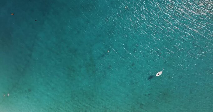 Aerial view of a boat sailing on the tranquil turquoise waters alongside swimmers in Erchie, Amalfi Coast, Italy.