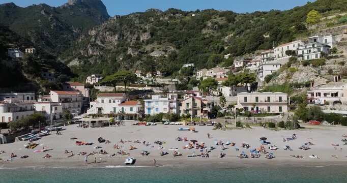 Aerial view of Erchie beach and houses nestled against the dramatic mountains, presenting a stunning contrast of turquoise water and verdant greenery, Erchie, Amalfi Coast, Italy.