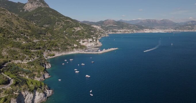 Aerial view of the Erchie coastline with the azure sea contrasting with lush green mountains and white boats, Erchie, Amalfi Coast, Italy.