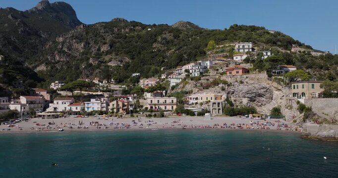 Aerial view of Erchie beach, a coastal scene with sunbathers, clear water, and hillside buildings, creating a vibrant, scenic view, Erchie, Amalfi Coast, Italy.