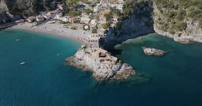 Aerial view of the vibrant Erchie beach with its historic coastal tower, set against the turquoise sea and rocky cliffs, Erchie, Amalfi Coast, Italy.