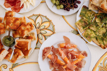 Assorted gourmet Italian  food spread featuring fresh fruits, cured meats, and artisan bread on decorative table, showcasing culinary delights and presentation