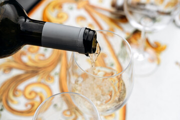 White wine being poured into a glass, showcasing the elegant flow and reflections on a beautifully designed table setting