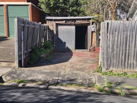 A slowly disintegrating small garage, only able to accommodate a tiny car, stands in disrepair at the rear of a property. Urban decay merges with creativity in this gritty street scene.