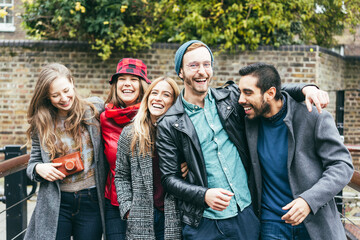 Group of friends walking around city in winter time - Young students having fun laughing and chatting together - Lifestyle, travel and friendship concept - Main focus on center blond girl
