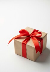 Obraz premium A gift box wrapped in brown kraft paper and tied with a red ribbon bow. Vertical present isolated on a white background with copy space for text. Holiday celebration concept