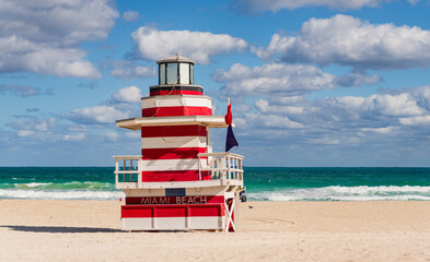Fototapeta premium Lifeguard over Miami beach. Panoramic seascape of famous coastline. Summer in Miami Beach. Miami Beach jetty. Rescue tower against the blue sky in Miami. Beautiful coastal view of Florida.