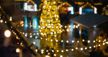Defocused people celebrating Christmas at a Christmas market decorated with Christmas trees and...