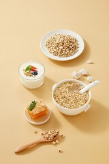 Composition of puffed coix seeds and raw grains with flying seeds effect, healthy cereal snack concept on beige background.
