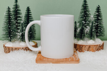 Ceramic mockup mug on cup coaster with christmas trees on green background. Mockup mug with copy space for winter design, Christmas and New Year concept