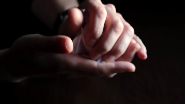 Hands crumpling clean paper sheet close-up on black background. Macro shooting of crumpled sheet. The concept of relieving tension, stress and anxiety. Side view. High quality 4k footage.