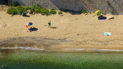 Aerial view of people on holiday on a sandy beach.
