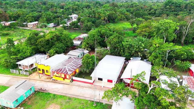 sweeping drone view over a remote riverside community on the Amazon River, Brazil, South America &mdash; small houses bordered by dense rainforest in a vibrant natural setting