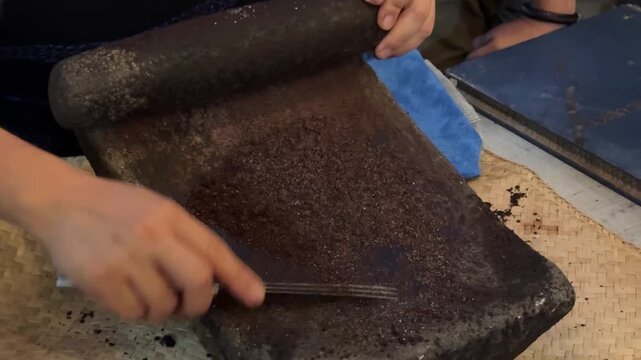 Grinding Cocoa Beans on a metate and mano to Make Chocolate in Guatemala 