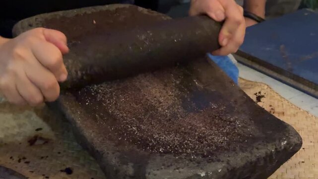 Grinding Sugar with Cocao Beans on a metate and mano to Make Chocolate in Guatemala 