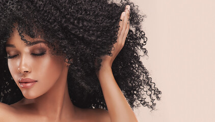 Beauty portrait of african american woman with clean healthy skin on beige background. Smiling...