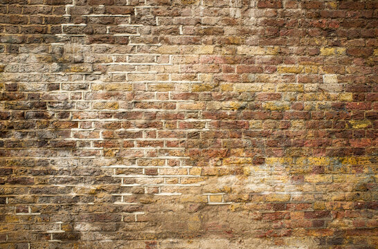 Brick Wall. Full frame texture of an old, weathered brick wall with varied colours and decaying mortar capturing the grunge, vintage and aged qualities suitable for backgrounds, textures and surfaces.