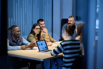 Diverse business team gathered around a table discussing analytics during a meeting in a modern...