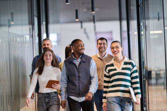 Group of confident professionals walking together through a bright modern office corridor. Concept of teamwork, diversity, success, collaboration, and positive workplace culture.