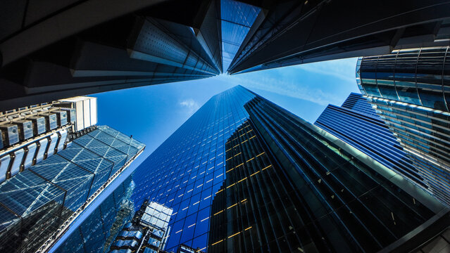 Modern skyscrapers and glass office buildings in business district, captured from low angle perspective with blue sky, symbolizing architecture, urban growth, corporate success, and city development.