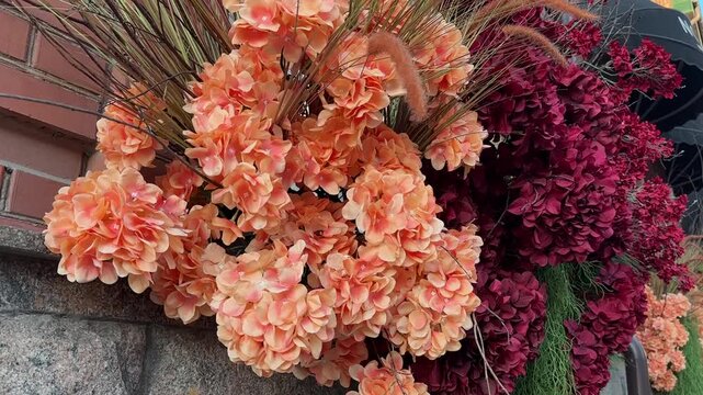 Decoration of artificial flowers and plants on the facade of the building. Orange and red hydrangea flowers