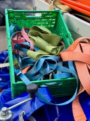 Colorful tie down straps in green plastic crate