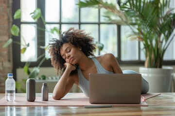Young woman relaxing on yoga mat with laptop