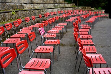 One pink chair among rows of red chairs