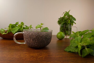 Chia seeds in glass cup with mint on wooden table.