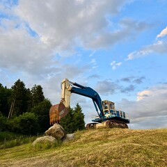 Blue excavator on construction site at sunset