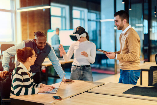 Group of creative professionals collaborating in a modern office using virtual reality headset and digital devices, representing innovation, teamwork, and futuristic workplace technology.