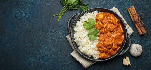 Indian chicken tikka masala in a creamy tomato sauce, served with basmati rice, fresh coriander and spices, traditional dish of India top view, copy space