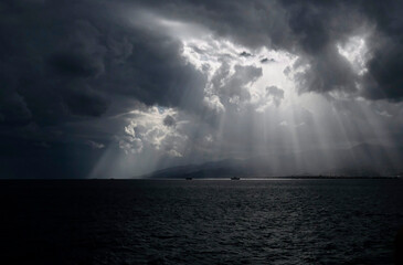 Sunlight breaking through the clouds, seen from the ferry between Calabria and Sicily in Italy