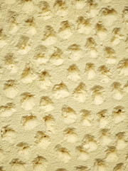 Decorative wall panel in pale yellow colonial style with a soft plaster texture featuring numerous small indentations