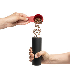 High quality PNG of pouring a portion of coffee into a manual coffee grinder