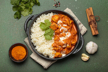 Aromatic Indian chicken tikka masala served with rice and coriander, turmeric, garlic, cinnamon sticks, traditional dish of India top view