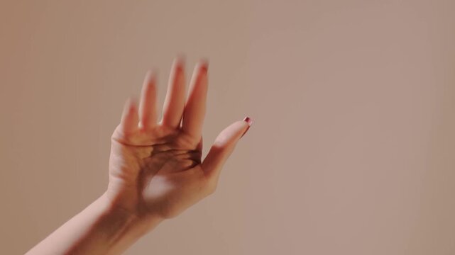 Closeup of elegant hand with glossy red manicure waving farewell slowly toward the camera in a tender goodbye gesture, a poignant parting pose that conveys warmth affection relationship bond