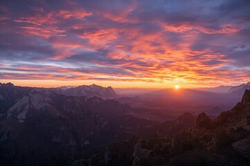 Colorful sky with mountain silhouettes and the sun at dawn and dusk