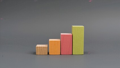 Colorful wooden blocks representing a financial growth chart with four stages on a dark background