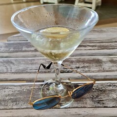 Refreshing cocktail with lemon and sunglasses on wooden table