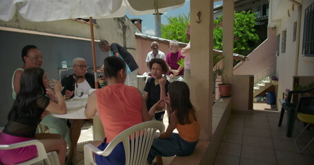 Lively group enjoying drinks and conversation around a table on a house terrace patio, creating a...