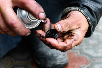 A car mechanic cleaning the body part of an old oil filter using a special cleaner.