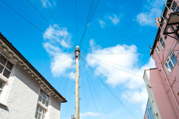 Tall, wooden telegraphy pole seen with many telephone and internet broadband cables which are connected nearby houses in a typical British street.