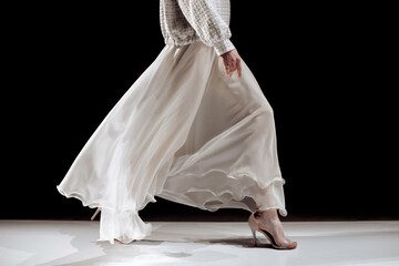Satin long white skirt and beige high heels, fashion cloth woman's elegant outfit on black background, fashion model walking the runway fashion show