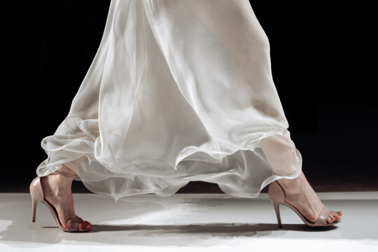 Satin long white skirt and beige high heels, fashion cloth woman's elegant outfit on black background, fashion model walking the runway fashion show