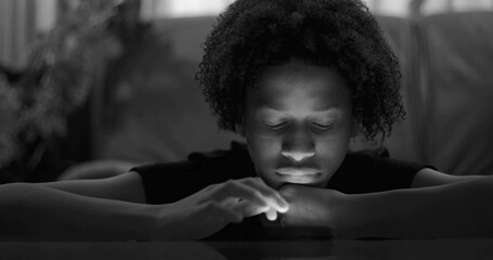 Close-up of boy leaning on table, smartphone glow on face, blank expression, emphasizing digital...